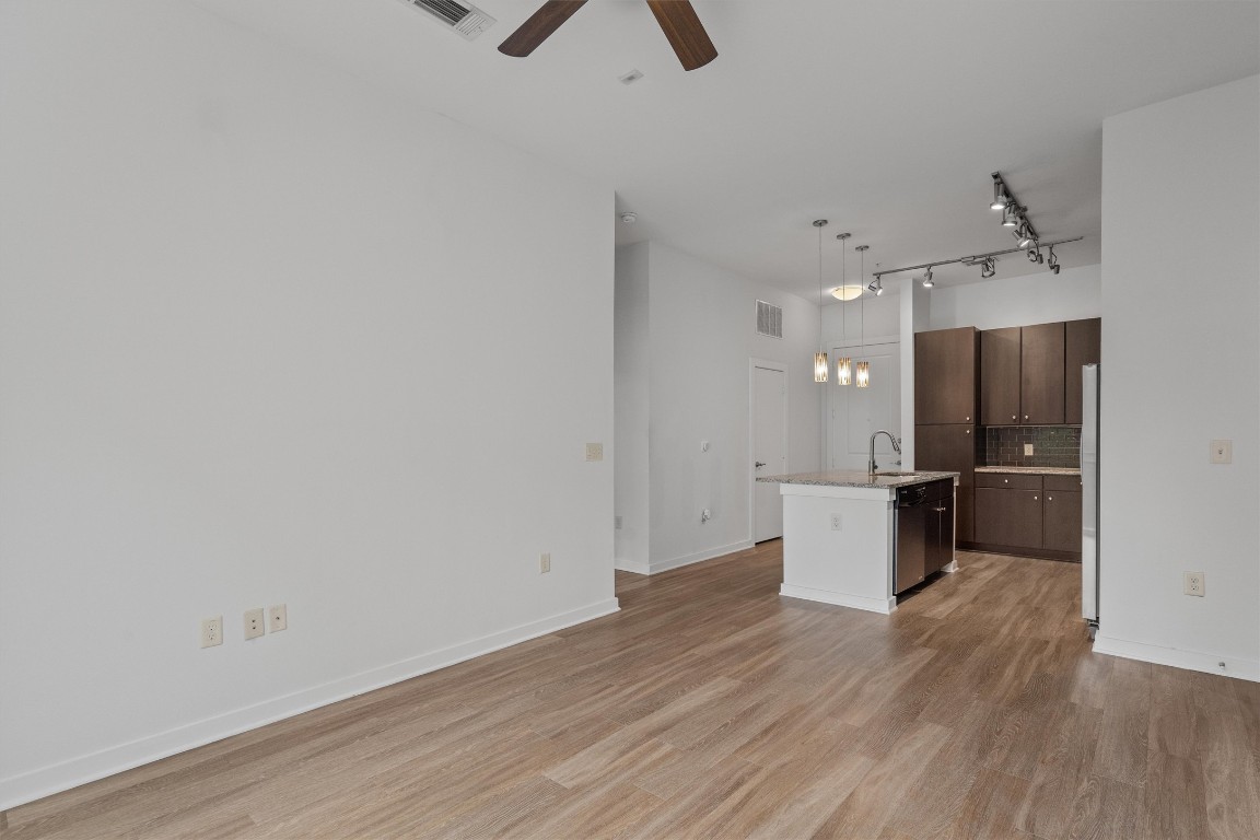 1900 Barton Springs Road, Unit 2027 Austin, TX 78704 - Photo 10 of 28 Kitchen with a center island with sink, hanging light fixtures, dark brown cabinets, light wood finished floors, and decorative backsplash