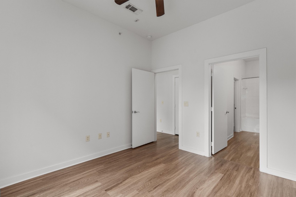 1900 Barton Springs Road, Unit 2027 Austin, TX 78704 - Photo 14 of 28 Unfurnished bedroom featuring light wood-style floors, a ceiling fan, and connected bathroom