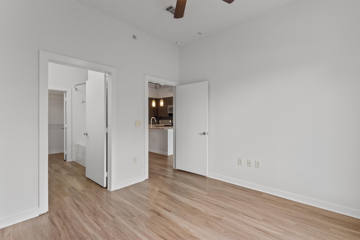 1900 Barton Springs Road, Unit 2027 Austin, TX 78704 - Photo 19 of 28 Unfurnished bedroom featuring light wood-style floors, a ceiling fan, and ensuite bath