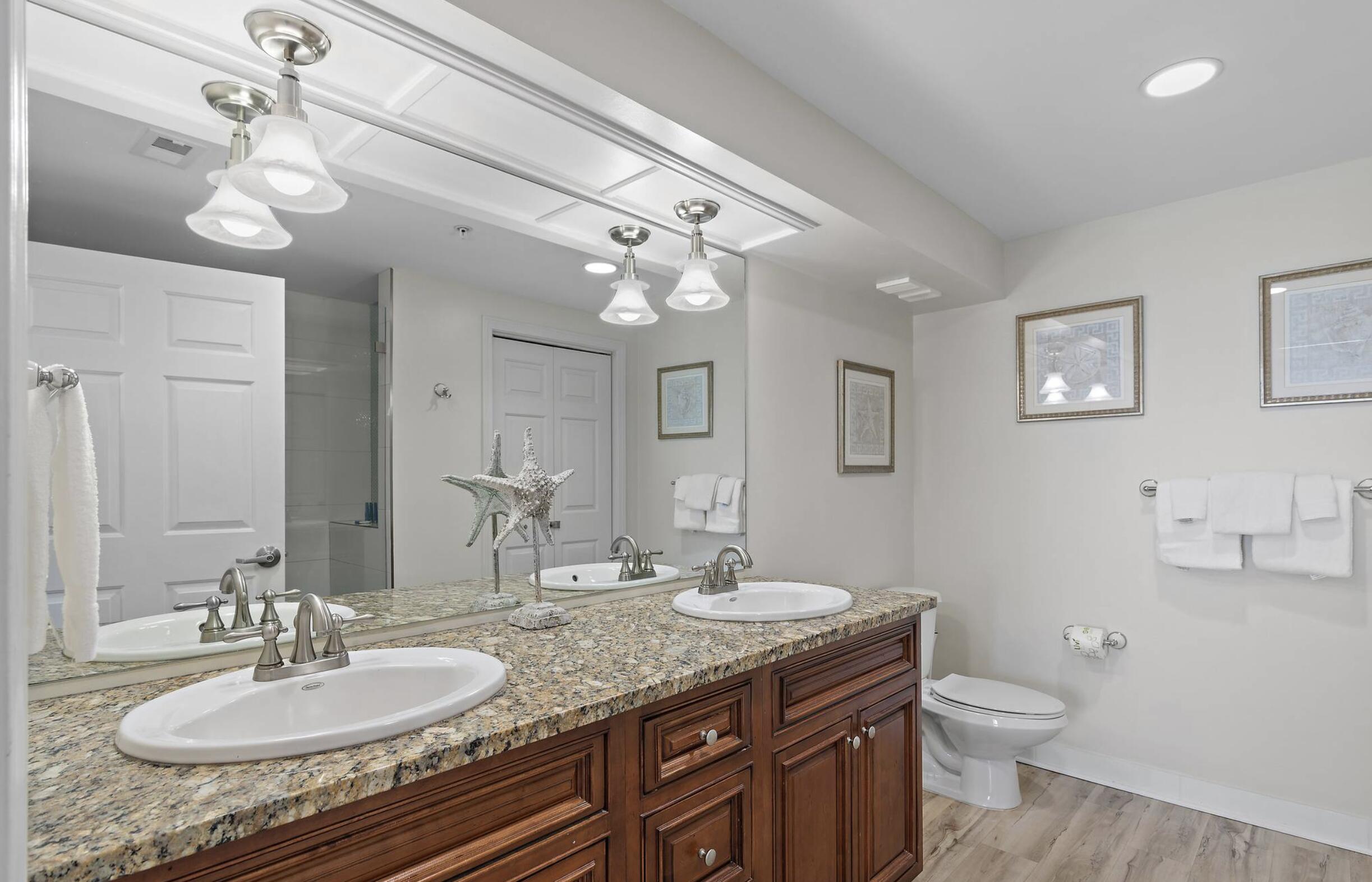 4789 Westwinds Drive, Unit 4789 Miramar Beach, FL 32550 - Photo 17 of 32 a bathroom with a granite countertop double vanity sink a toilet and a mirror