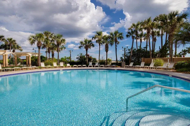 a view of swimming pool with outdoor seating and trees in the background