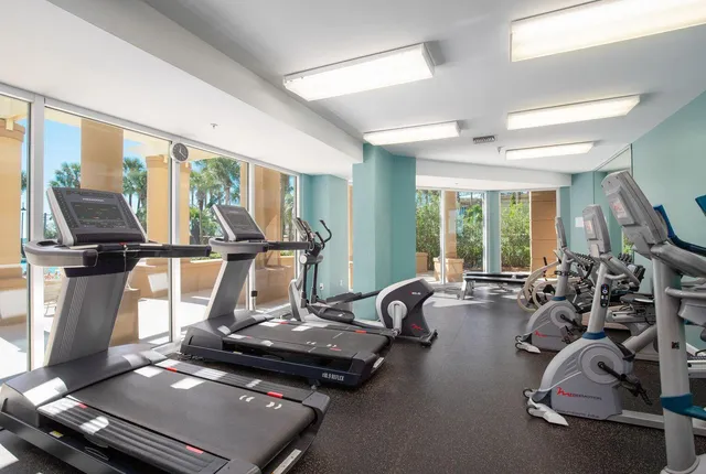 a room with gym equipment and large windows