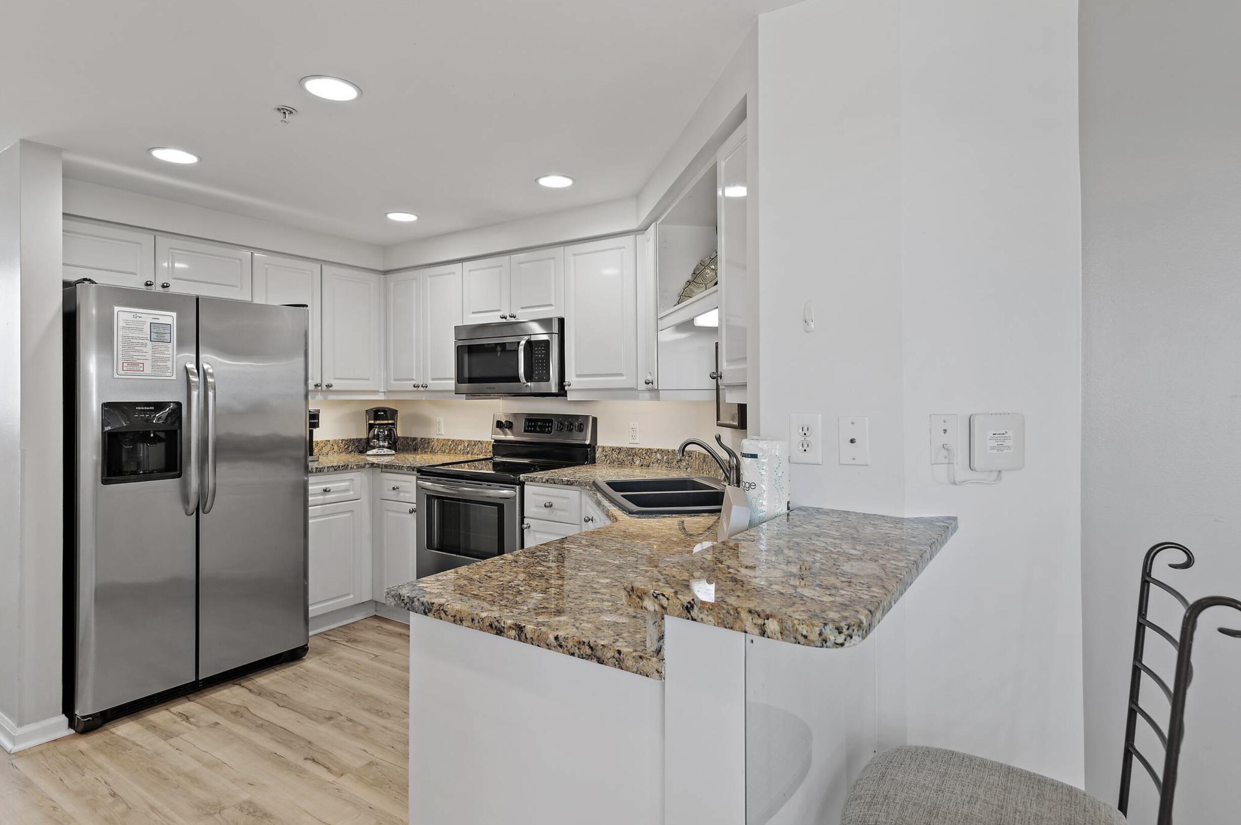 4789 Westwinds Drive, Unit 4789 Miramar Beach, FL 32550 - Photo 6 of 32 a kitchen with stainless steel appliances granite countertop a refrigerator a stove a sink and a microwave