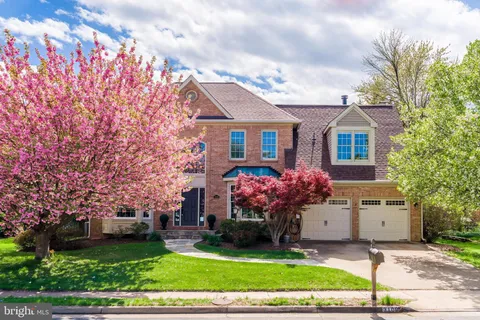 a front view of a house with a garden and trees