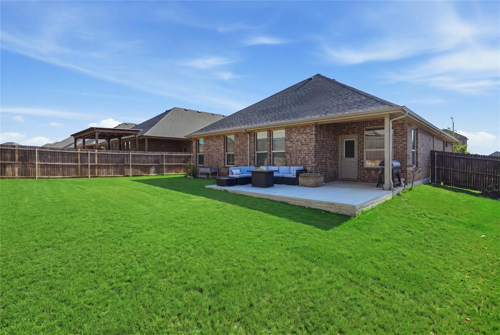 1812 Ruffian Road Granbury, TX 76049 - Photo 32 of 37 Expansive backyard with a manicured lawn, brick exterior, covered concrete patio, and privacy fencing