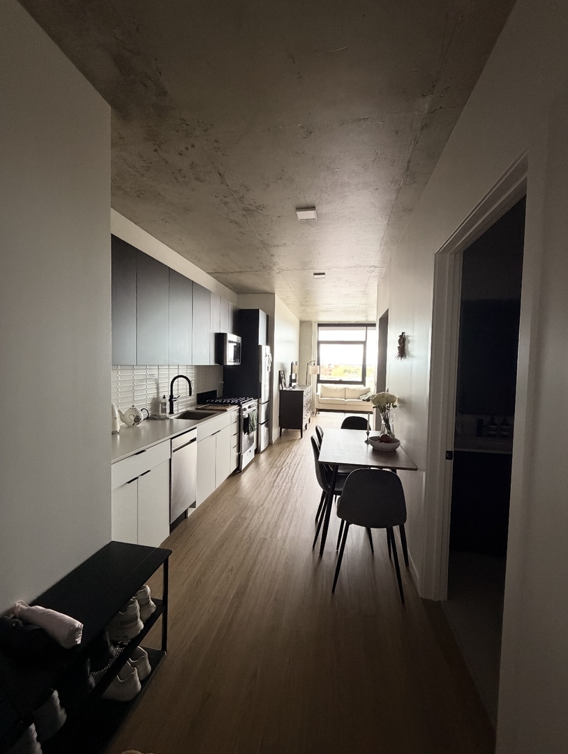 225 North Elizabeth Street, Unit 514 Chicago, IL 60607 - Photo 3 of 13 a kitchen with granite countertop a refrigerator a sink dishwasher a dining table and chairs with wooden floor