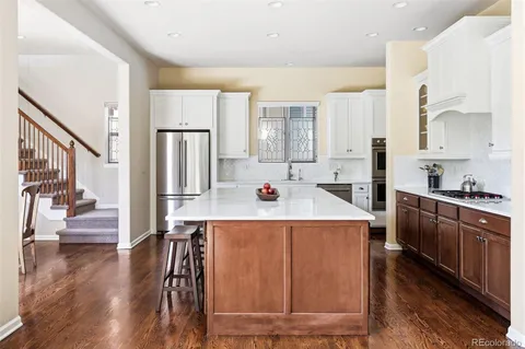 a view of kitchen with stainless steel appliances wooden floor dining table and chairs