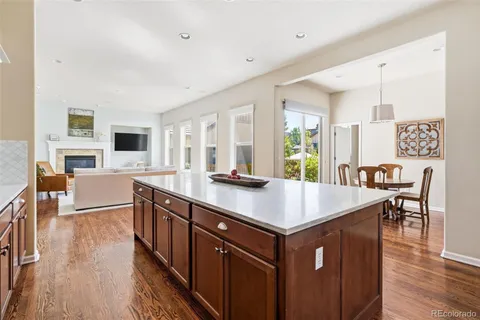 a kitchen with stainless steel appliances granite countertop a table chairs sink and wooden floor