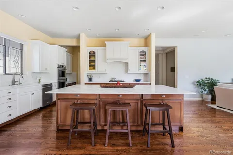 a dining hall with stainless steel appliances granite countertop a table chairs sink and wooden floor