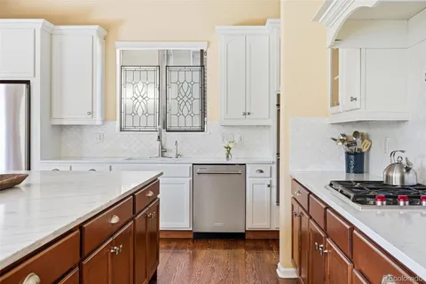 a kitchen with a sink cabinets stainless steel appliances and wooden floor
