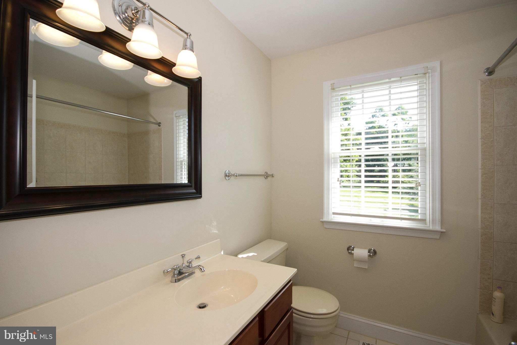 1907 Ridge Road Reisterstown, MD 21136 - Photo 20 of 27 a bathroom with a toilet a sink a mirror and a window