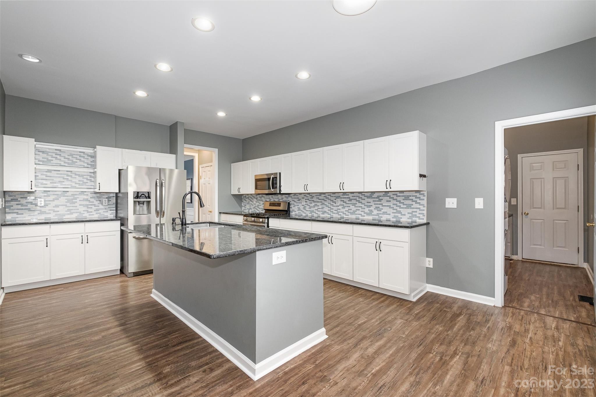 765 Knightswood Road Fort Mill, SC 29708 - Photo 15 of 41 a kitchen with stainless steel appliances granite countertop a refrigerator a sink dishwasher a stove and white cabinets with wooden floor