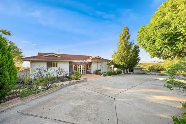 a view of house with outdoor space and tree in front of it