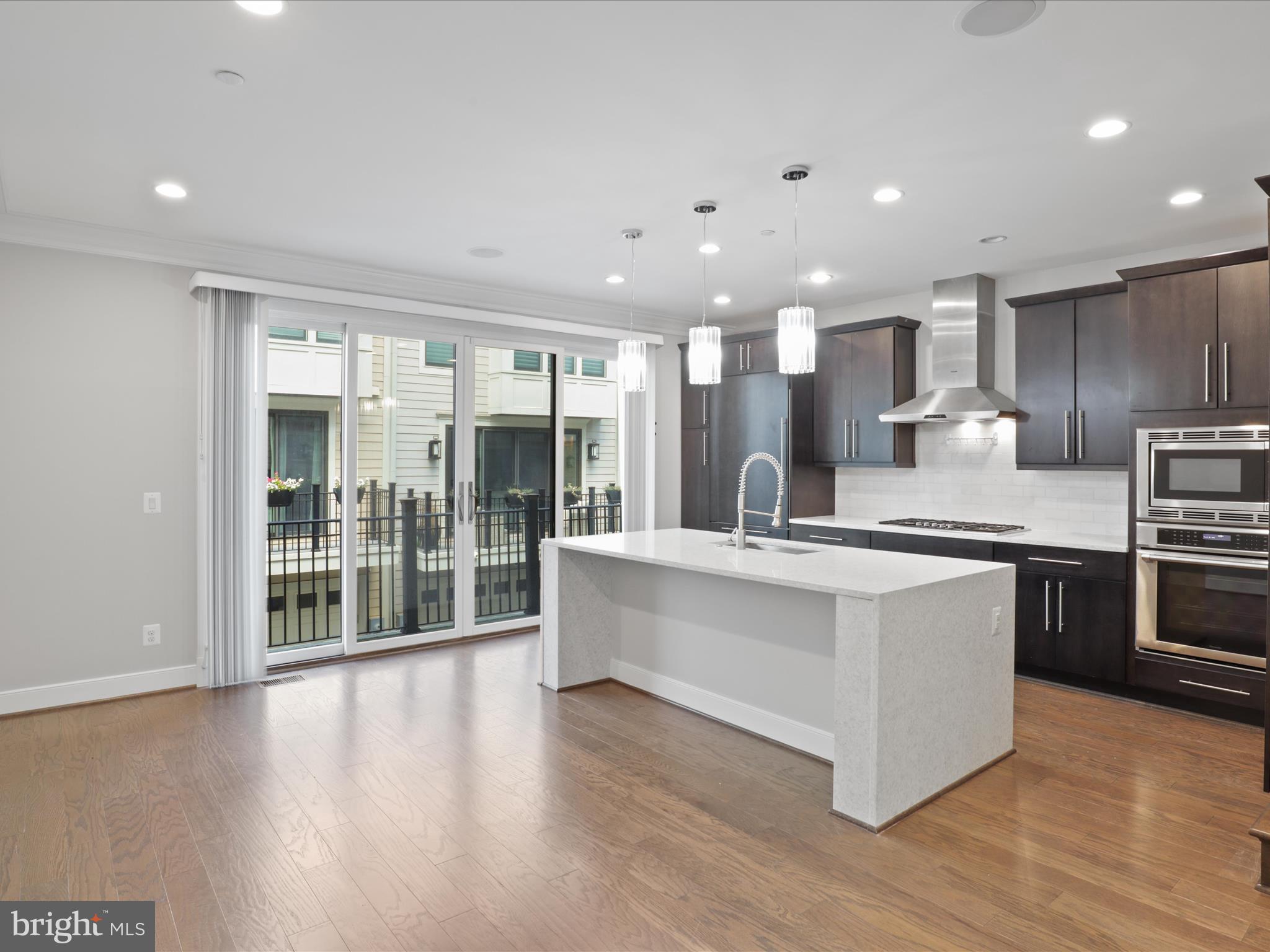 1521 16th Road North Arlington, VA 22209 - Photo 19 of 59 a large white kitchen with kitchen island a large counter top and stainless steel appliances