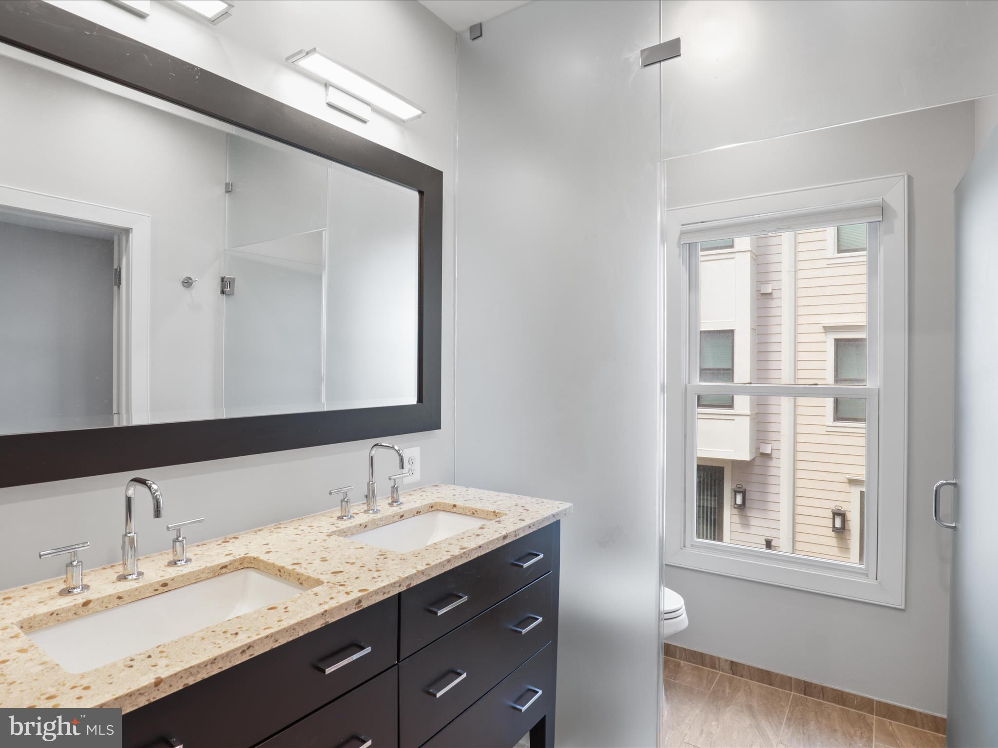 1521 16th Road North Arlington, VA 22209 - Photo 29 of 59 a bathroom with a granite countertop sink a large mirror and a window