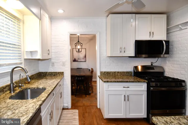 a kitchen with granite countertop a sink a stove and cabinets