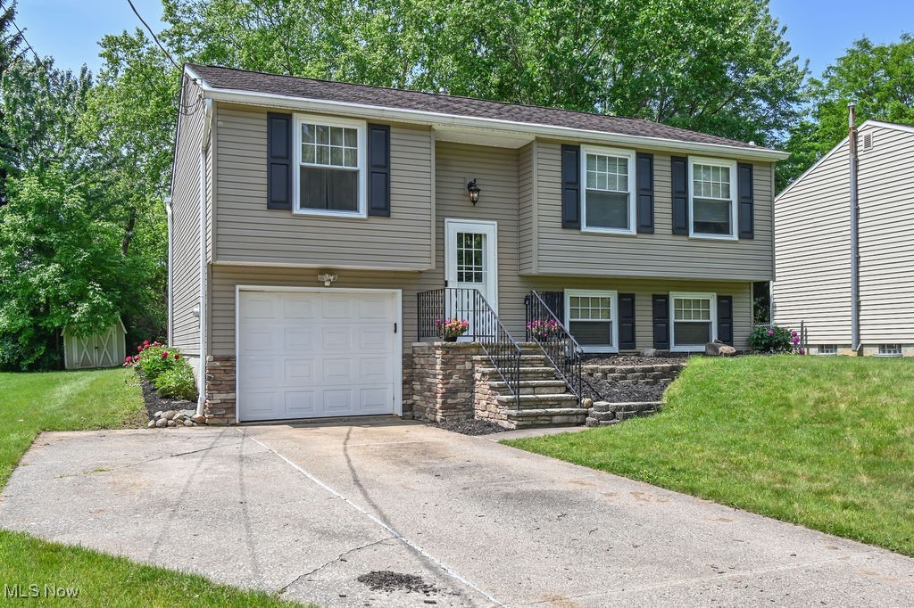 2610 Norton Road Stow, OH 44224 - Photo 3 of 41 Split level home with an attached garage, a front yard, concrete driveway with extra parking space, and stone siding. Flower beds planted with perennials & was mulched before listing.