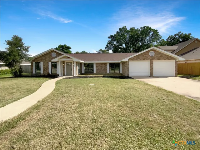 a front view of a house with a yard and trees