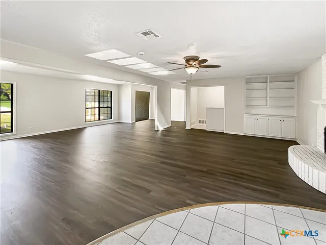 a view of an empty room with window and wooden floor