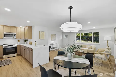 a kitchen with stainless steel appliances kitchen island granite countertop a dining table chairs and white cabinets