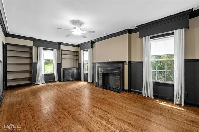 a view of an empty room with wooden floor fireplace and a window