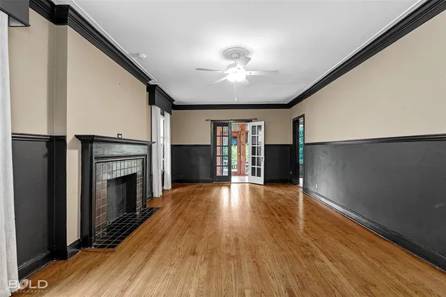 a view of an empty room with wooden floor fireplace and a window