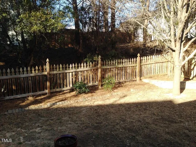 a view of backyard with wooden fence and trees