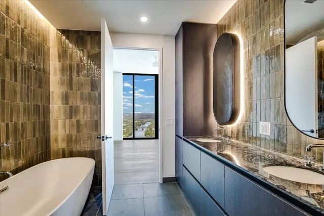 a bathroom with a granite countertop tub sink and mirror