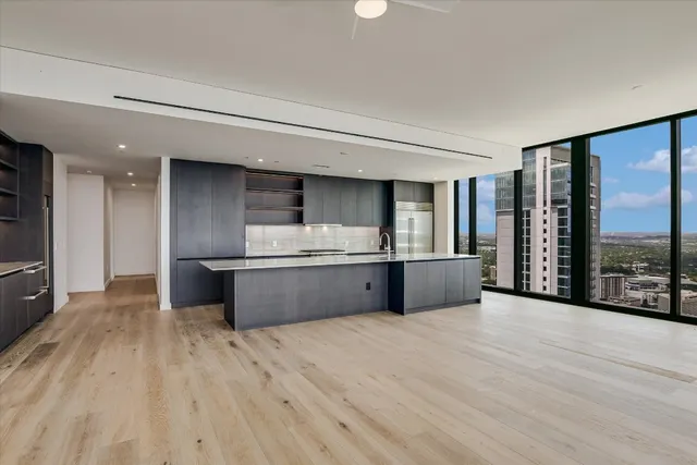 a large kitchen with stainless steel appliances wooden floors and large window