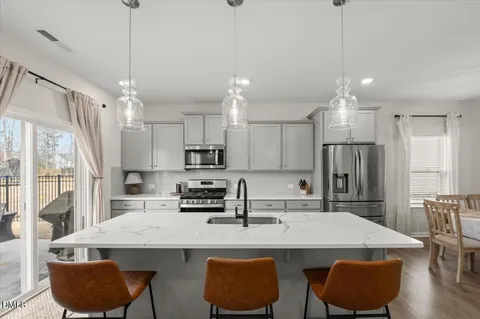 a kitchen with stainless steel appliances granite countertop a sink a stove a refrigerator cabinets and chairs