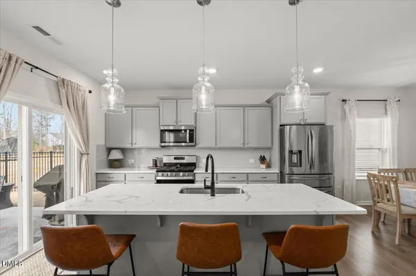 a kitchen with stainless steel appliances granite countertop a sink a stove a refrigerator cabinets and chairs