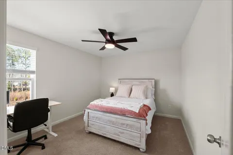 a bedroom with a bed a chair and a large window