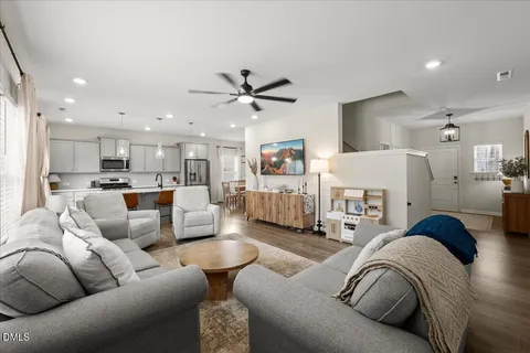 a living room with furniture kitchen view and a chandelier