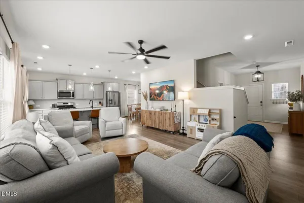 a living room with furniture kitchen view and a chandelier