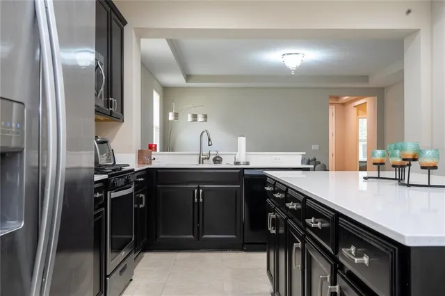 a kitchen with stainless steel appliances a sink a stove a microwave a refrigerator a counter space and cabinets