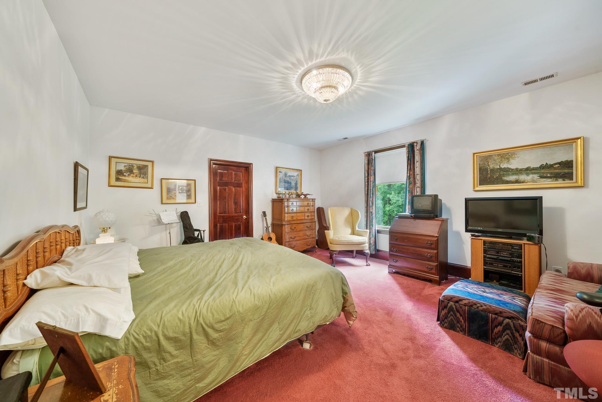 920 Windrow Lane Raleigh, NC 27603 - Photo 28 of 40 a spacious bedroom with a bed a couch and potted plant in it