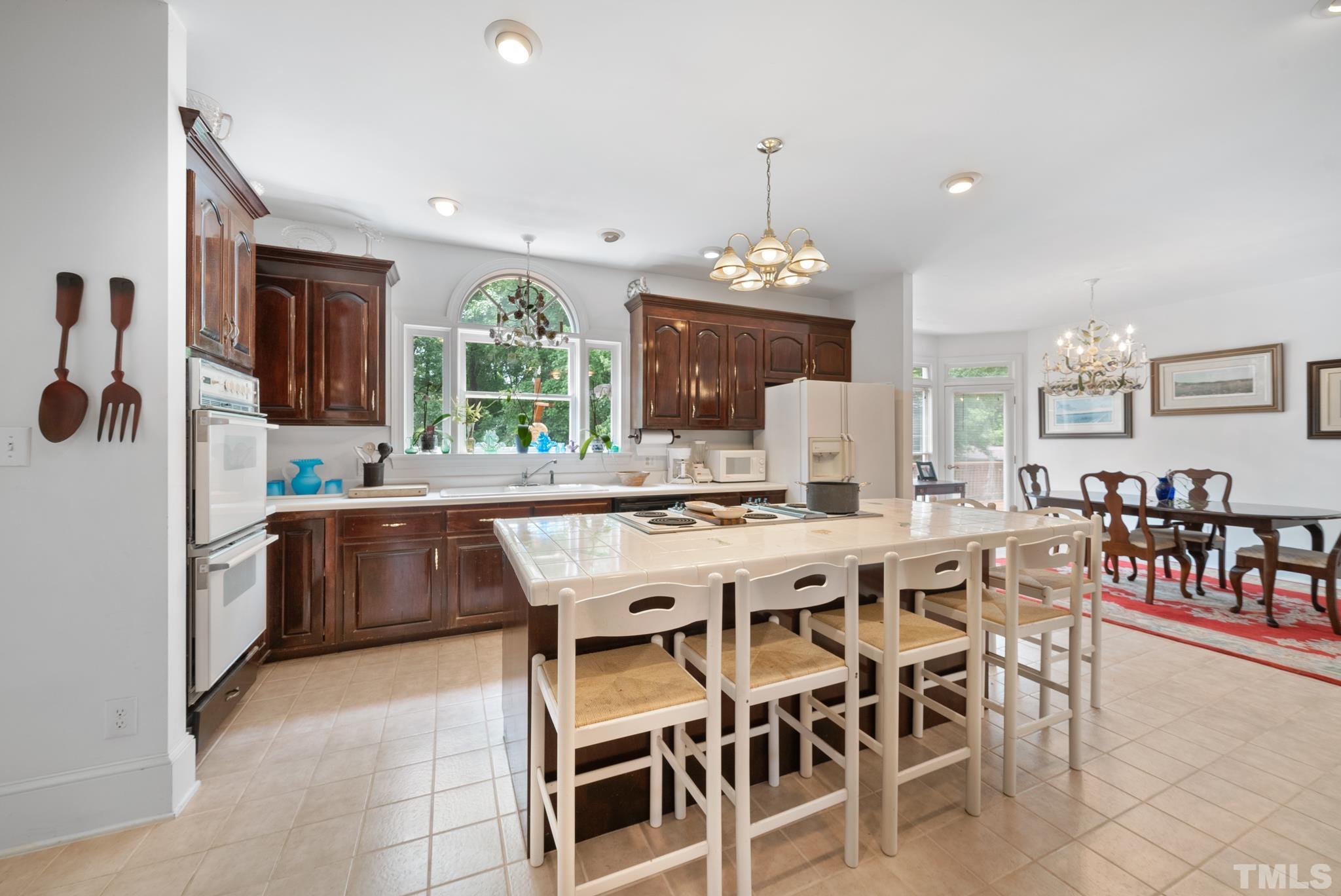 920 Windrow Lane Raleigh, NC 27603 - Photo 8 of 40 a kitchen with a dining table chairs sink and white cabinets