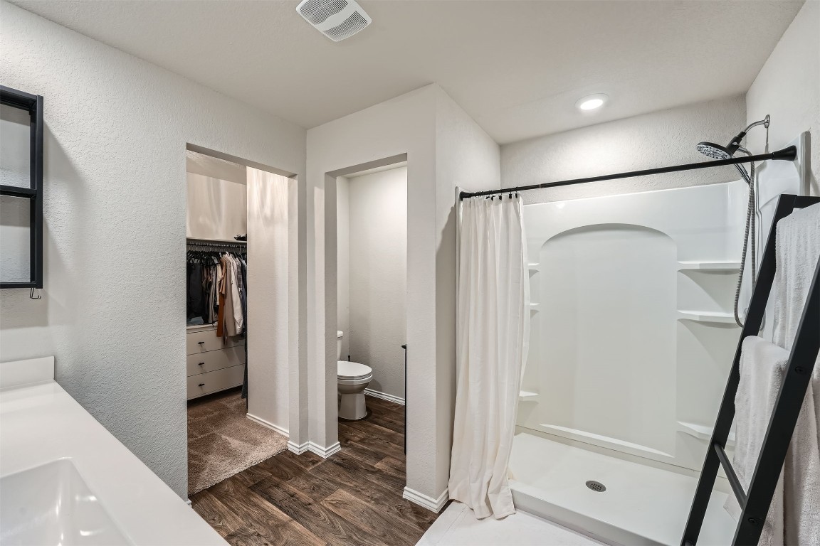 6404 Diamondleaf Bend Austin, TX 78724 - Photo 15 of 29 Full bathroom featuring a spacious closet, a shower stall, vanity, a textured wall, and dark wood finished floors
