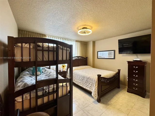 a spacious bedroom with a bed a flat screen tv and dresser
