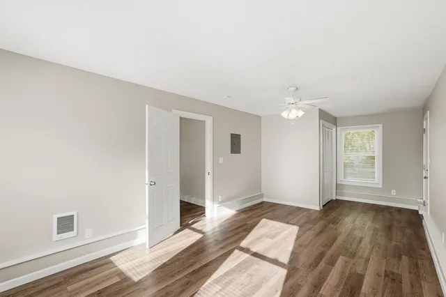 an empty room with wooden floor and windows