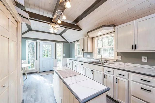 a large kitchen with kitchen island a large window a sink and stainless steel appliances