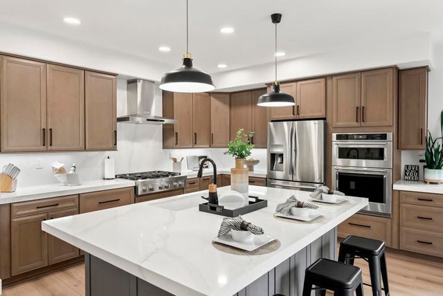 a kitchen with stainless steel appliances kitchen island granite countertop a sink a stove a refrigerator and a dining table with wooden floor