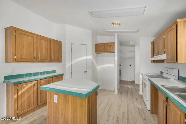 a kitchen with granite countertop a sink a stove cabinets and wooden floor