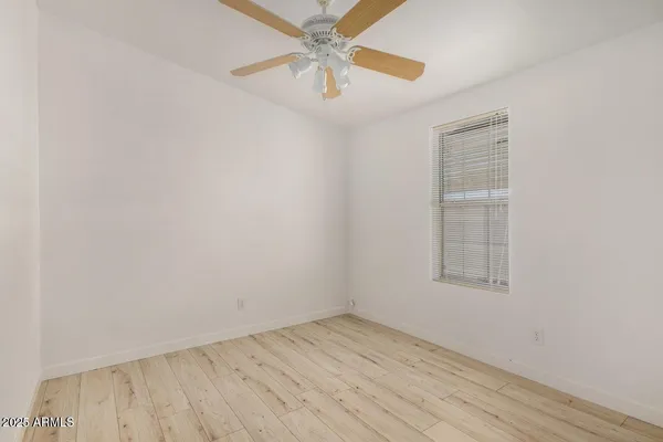 an empty room with a window and a fan