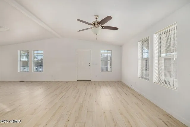 a view of an empty room with a window and wooden floor