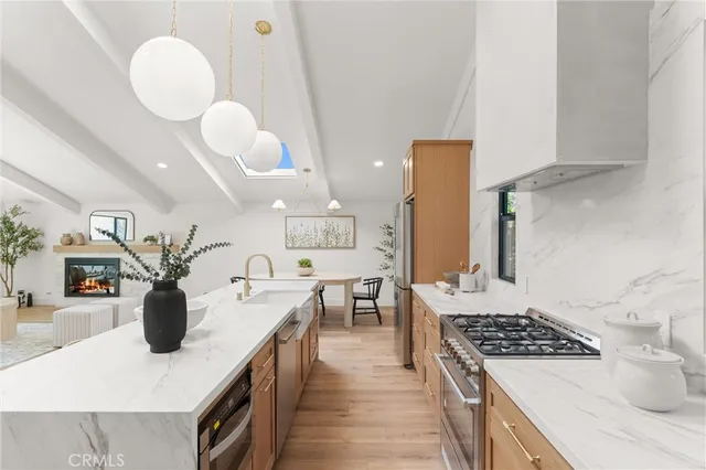 a kitchen with stainless steel appliances granite countertop a sink a stove and a wooden floors