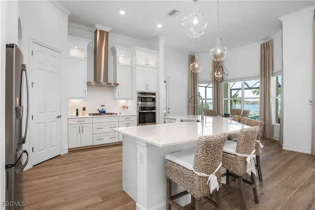 a large kitchen with cabinets chairs and wooden floor