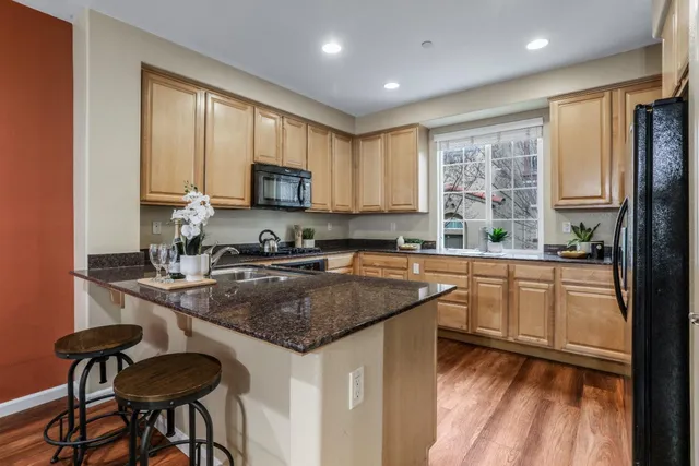 a kitchen with stainless steel appliances granite countertop a stove a sink dishwasher a microwave oven and a refrigerator with wooden floor