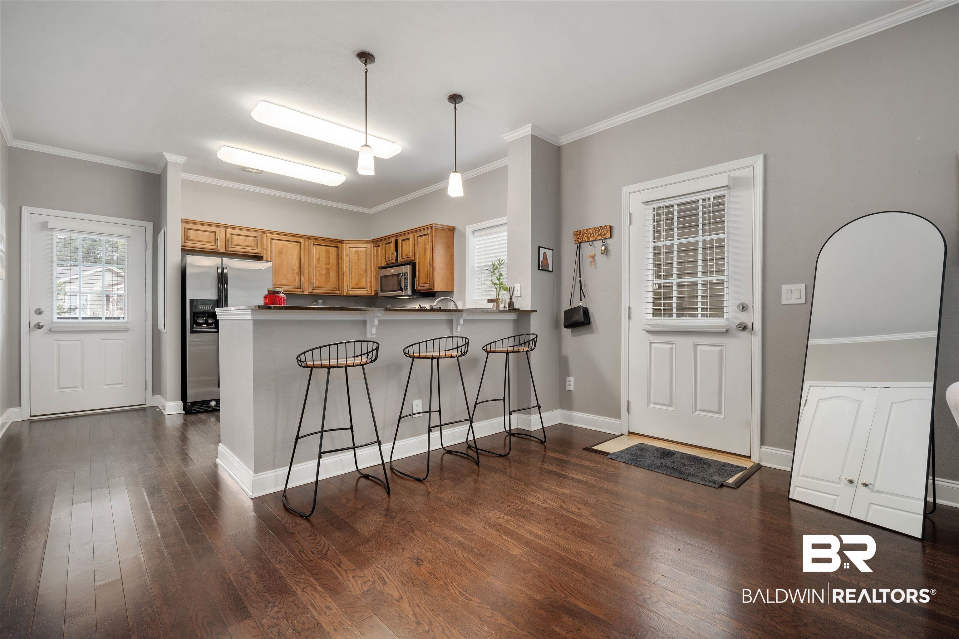 25806 Pollard Road, Unit 205 Daphne, AL 36526 - Photo 8 of 26 Kitchen featuring crown molding, a kitchen breakfast bar, stainless steel appliances, dark wood finished floors, and pendant lighting
