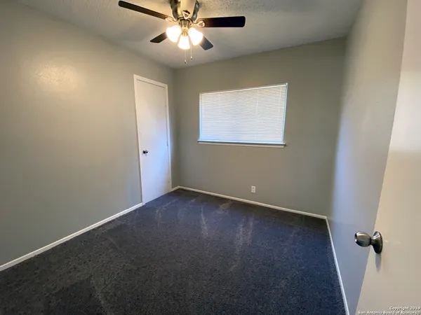 an empty room with a window and a fan